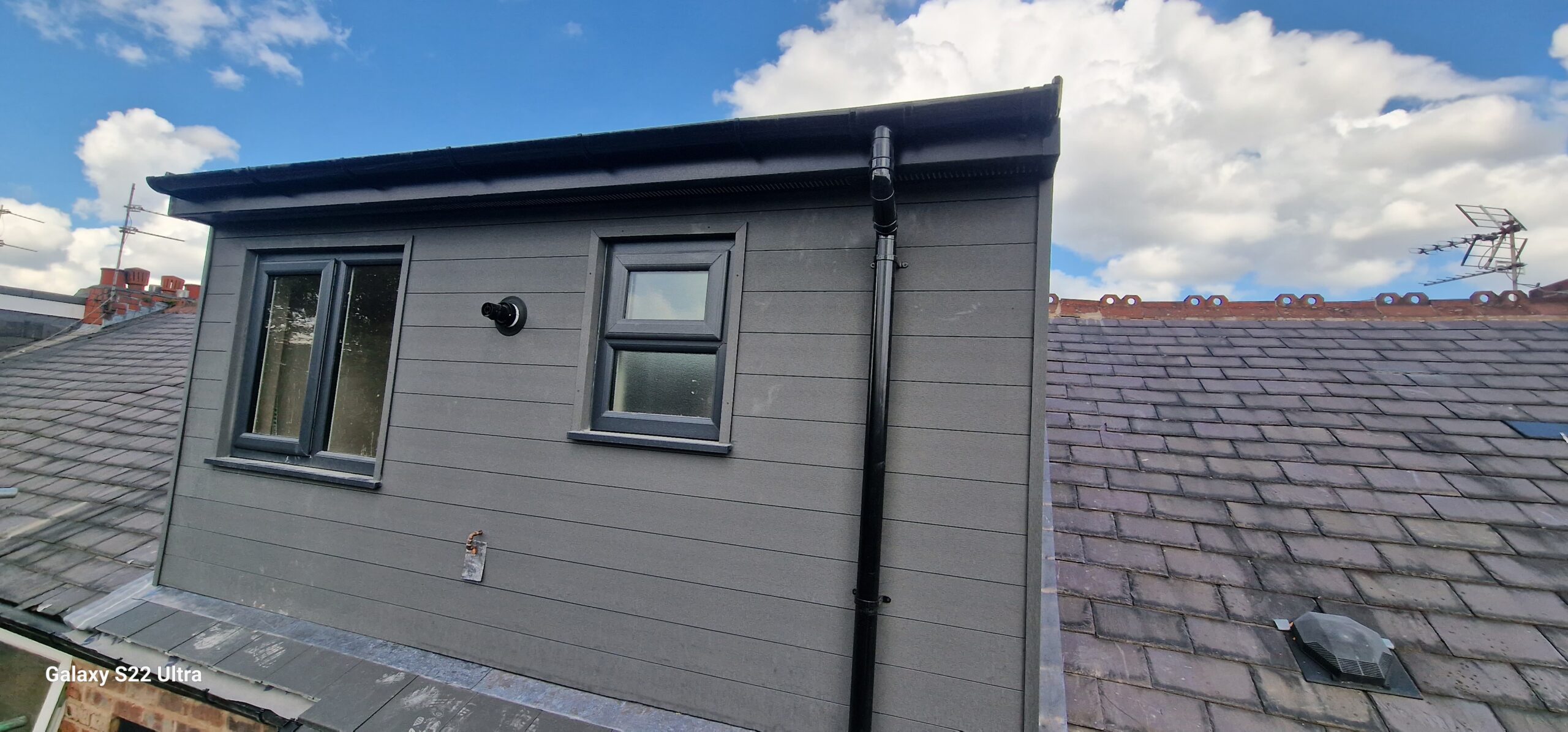 Completed grey dormer loft conversion exterior with windows, cladding, guttering and tiled roof by KWS Builders Manchester